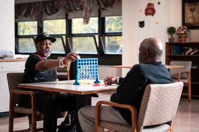 Residents playing Connect Four in an activity room