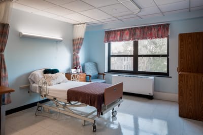 A prepared resident room with hospital bed and chair