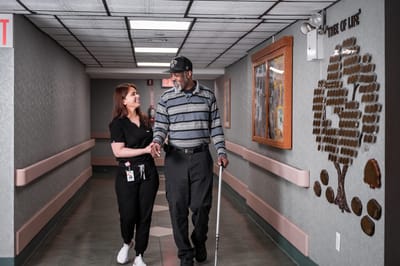 Staff member assisting a resident in a hallway