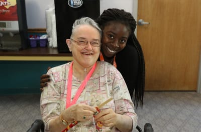 A caregiver embracing a smiling resident in a common area