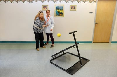 Therapist assisting a resident with an activity in a hallway