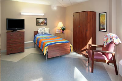 Cozy resident room with bed, dresser, and TV