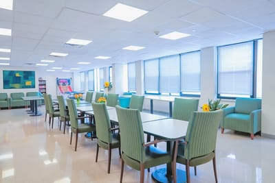 Bright common area with green chairs and tables