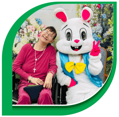 Resident posing with a mascot in a festive setting