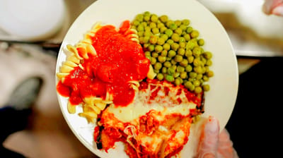 A plate of pasta, greens, and lasagna served in a caring environment