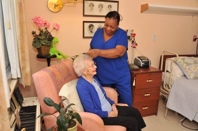 Caregiver assisting a senior resident in a cozy room.