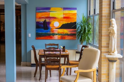 Brightly lit common area with dining table and artwork
