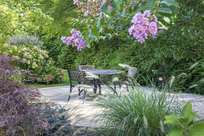 Outdoor seating area surrounded by flowers and greenery