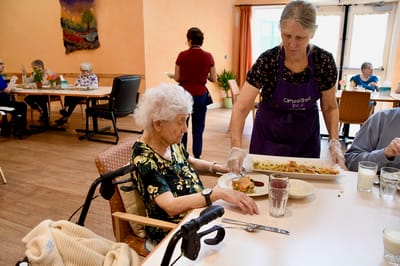Staff serving food to residents in a dining area