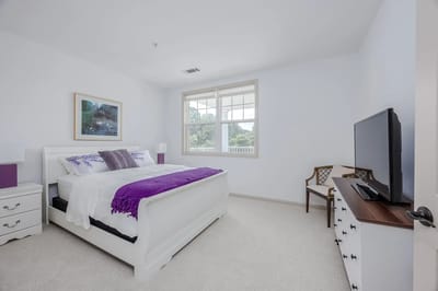 Bright, well-furnished resident room with a bed and TV