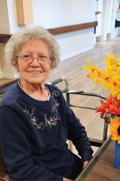 Senior resident smiling at a table with flowers