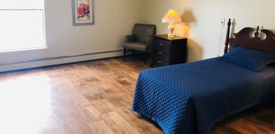 A private resident room with a bed and chair