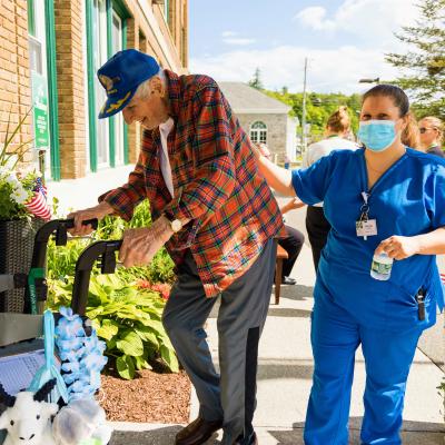 A resident assisted by staff outdoors at the facility