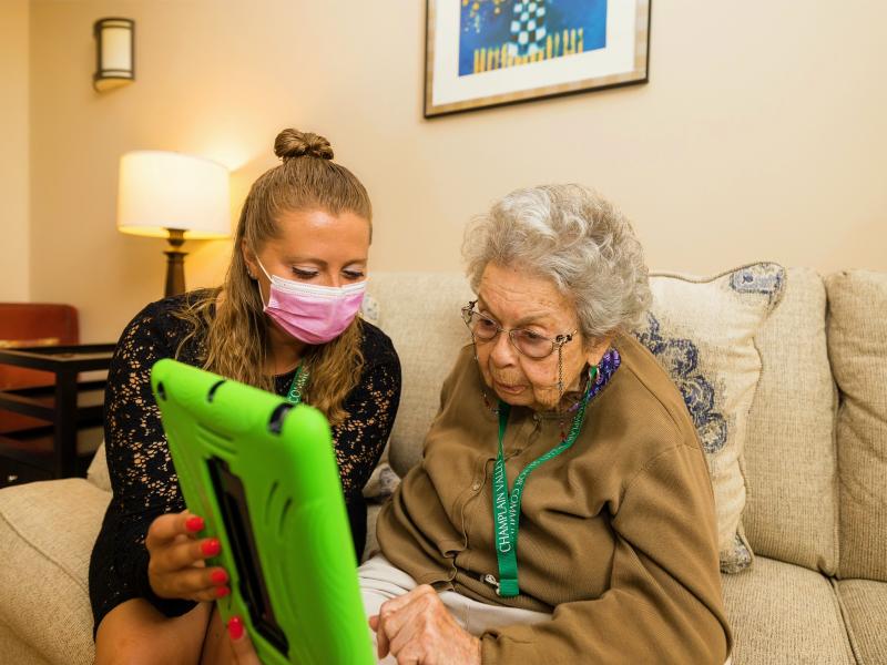 Caregiver assisting a resident with a tablet