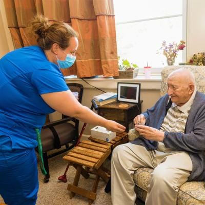 Staff assisting a resident in a cozy interior setting
