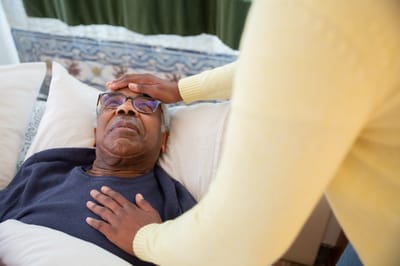 A caregiver checking on a resident in bed.
