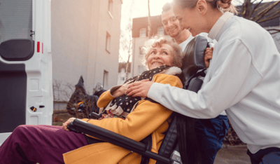 Care staff assisting a resident in a wheelchair outside