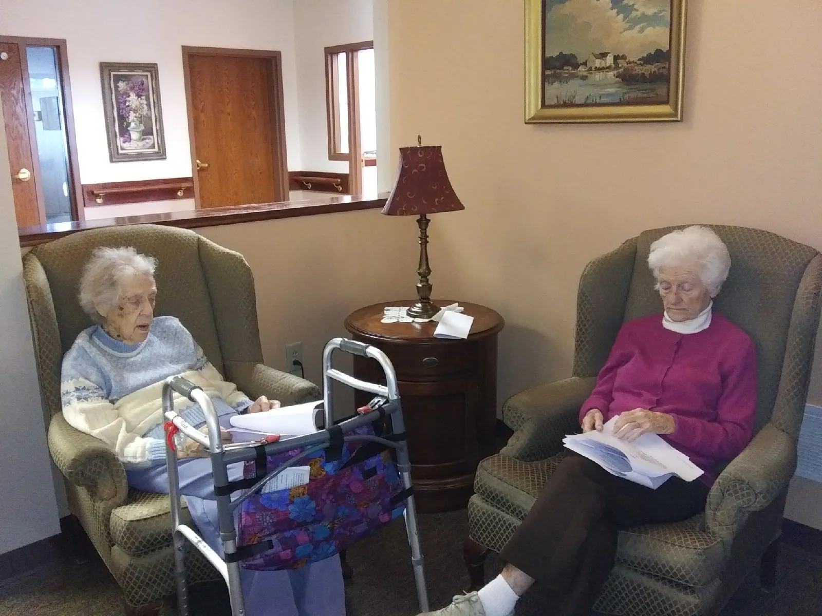 Two elderly women reading in a common area