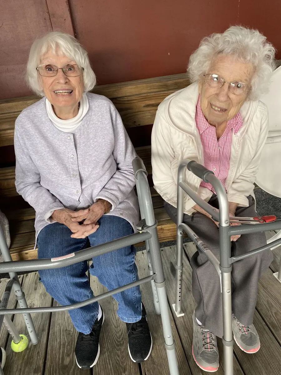 Two elderly women sitting on a bench smiling