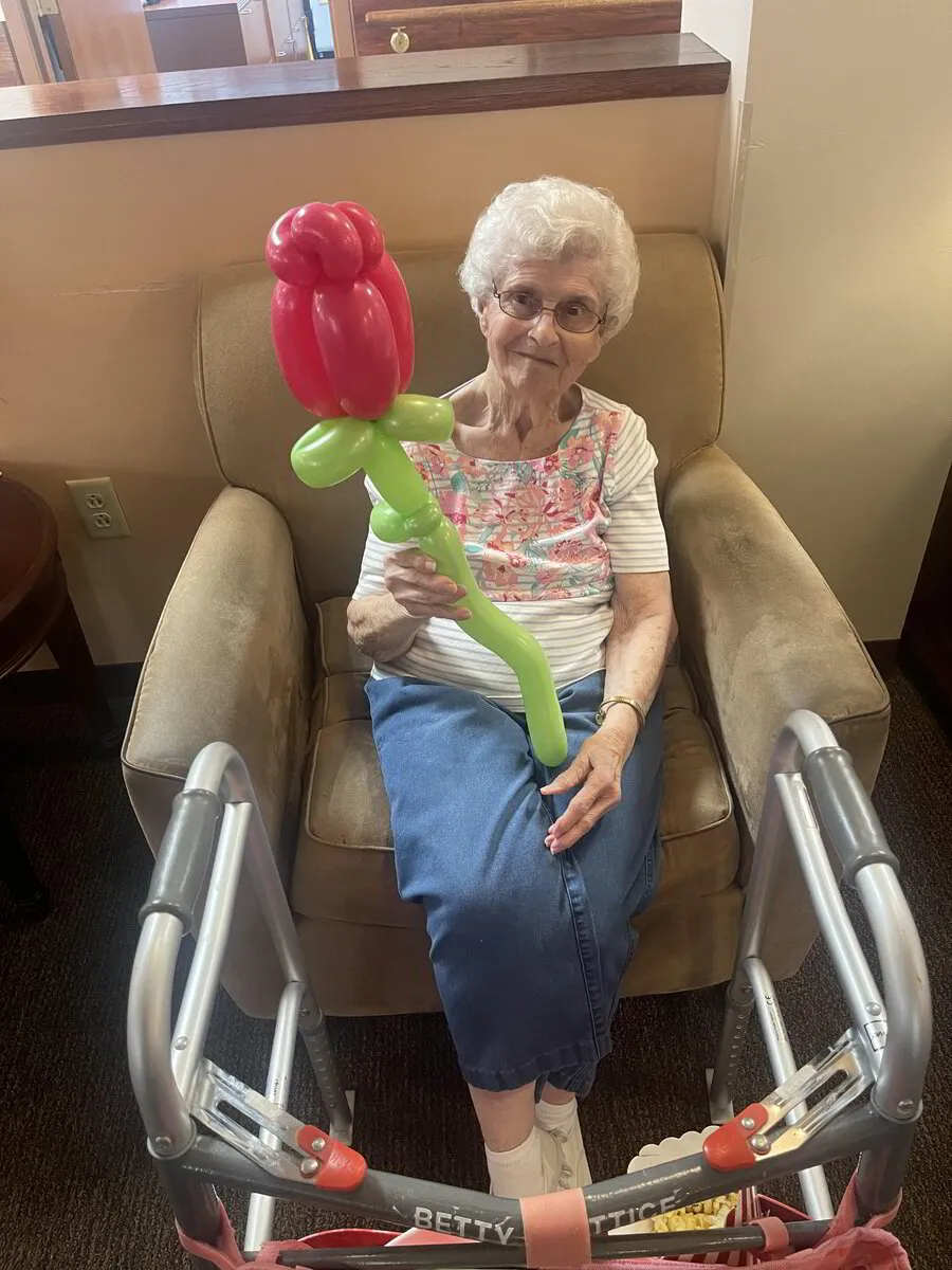 Resident holding a balloon flower in a cozy chair