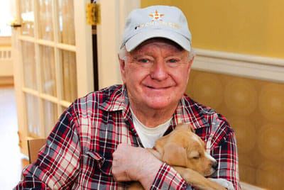 A resident holding a puppy in a bright indoor setting