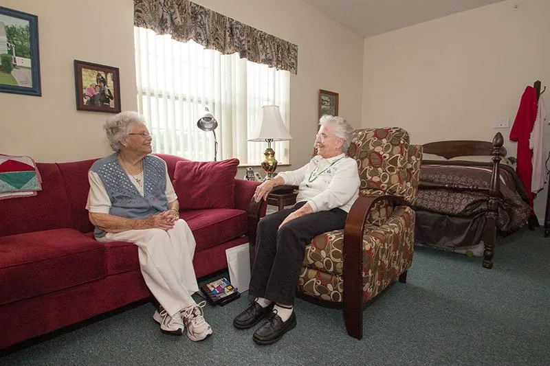Two elderly residents sitting and chatting in a cozy living room