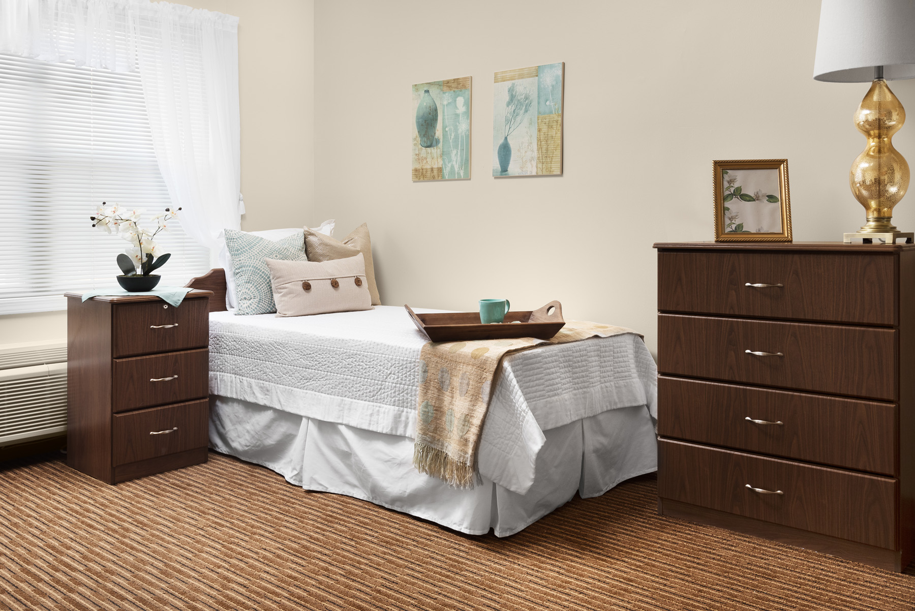 A beautifully decorated resident room showcasing a bed and nightstand
