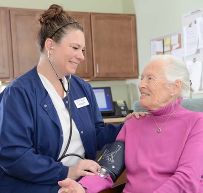 A nurse taking a resident's blood pressure in a comfortable setting