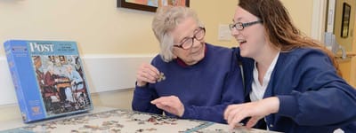 Resident and staff enjoying a puzzle together