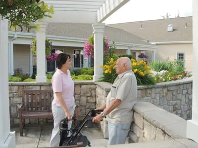 Staff assisting a resident in a garden area