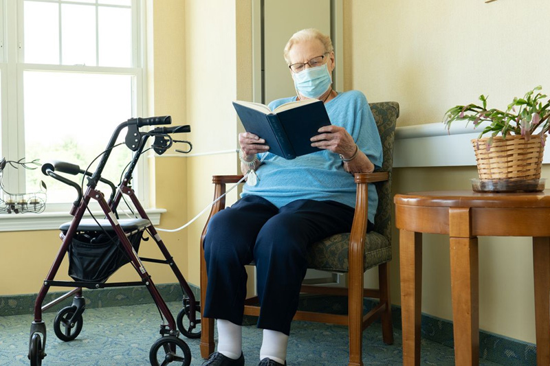 A senior reading a book in a cozy lounge area