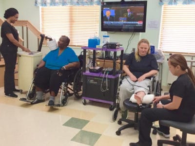 Therapists assisting residents in a rehabilitation area