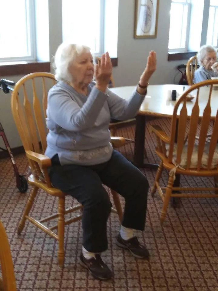 Resident engaging in seated exercise class in common area