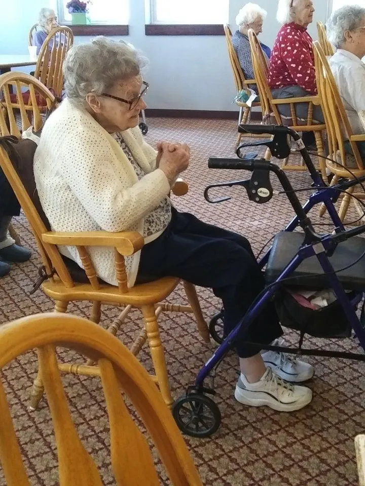 Resident sitting in a common area with others in the background