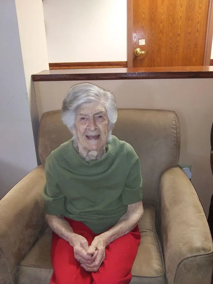 An elderly woman smiling while sitting in a chair