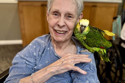 Resident smiling with a parrot on her shoulder