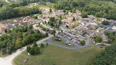Aerial view of a large assisted living facility with parking and greenery