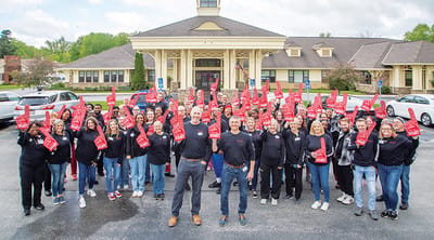 Staff and residents celebrating in front of the facility
