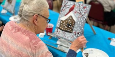 Resident painting a snowy scene during an art activity