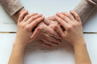 Hands of an elderly person and a child holding each other