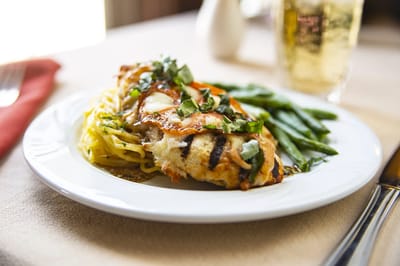 A plated meal with chicken, pasta, and green beans
