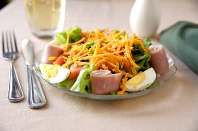 A plate of salad with ham, cheese, and boiled egg