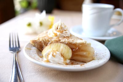 A slice of pie with whipped cream and a coffee cup