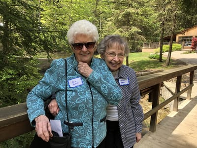 Two residents smiling on a bridge in a natural setting