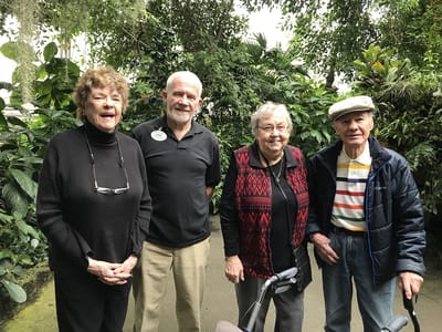Residents and staff smiling in a lush garden