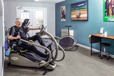 Resident exercising on a NuStep machine in the fitness area