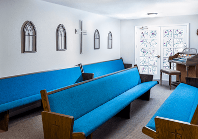 Quiet chapel with blue pews and decorative glass door