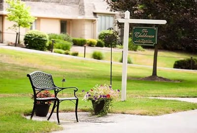 Outdoor seating area with flowers near the clubhouse sign
