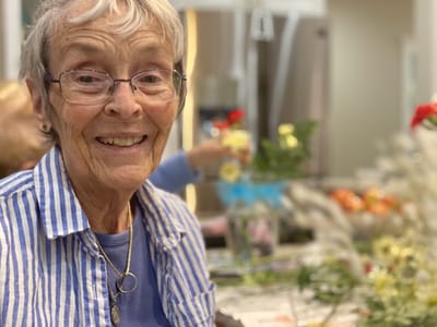 Resident smiling while arranging flowers indoors
