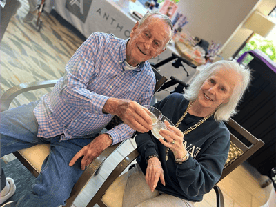 Two residents toasting with drinks in a communal space